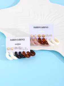 Macro view of colorful resin hoop earrings and mixed stud set on a white display board