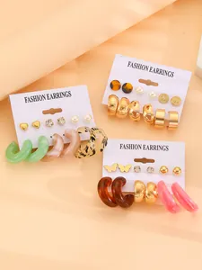 Detailed macro view of multiple colorful resin hoop earrings and mixed metal stud sets