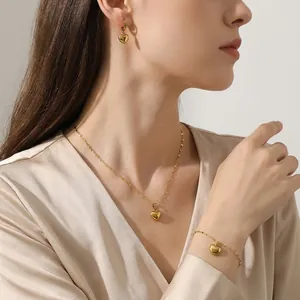 Model draagt een gouden hartensieradenset met oorbellen, ketting en armband