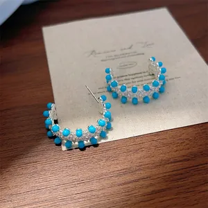 Detailopname van C-vormige oorringen met blauwe turkoois kralen en steentjes