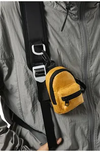 Primer plano de un mini bolso amarillo con forma de mochila colgado de la correa de una chaqueta