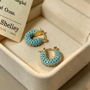 Detailweergave van vintage turquoise oorringen in een elegante beige sieradendoos