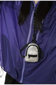 Vista detallada de un mini monedero de mochila plateado usado sobre una chaqueta lila