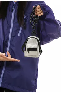 Primer plano de un mini mochila llavero plateado elegante con cordón negro ajustable