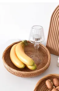 Vista detallada de la cesta redonda de ratán con plátanos decorativos y portavelas