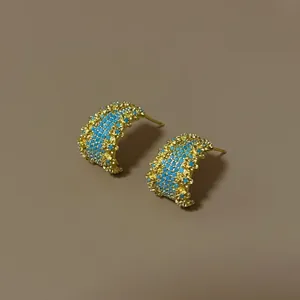 Close-up van elegante goudkleurige oorringen met turkoois steentjes in retrostijl