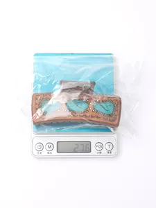 Pince à cheveux en cuir de style western pesant 27,6 g sur une balance numérique
