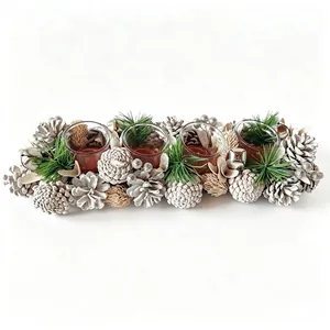Close-up of a Christmas centerpiece featuring four glass candle holders and pine cones