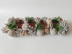 Detailed view of a festive candle holder centerpiece with pine cones and silver bells.