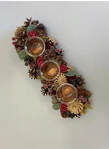 Detailed close-up of a Christmas wreath candle holder with pinecones, red roses, and berries