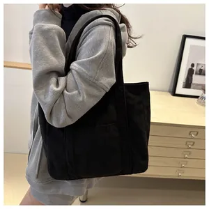 Black corduroy tote bag shown as a shoulder underarm bag on a model