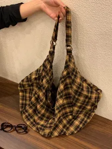 Détail d'un grand sac hobo en toile à carreaux vintage montrant la texture du tissu et le motif