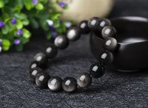Nahaufnahme des silbernen Obsidian-Armbandes mit intensivem Katzenaugen-Lichteffekt