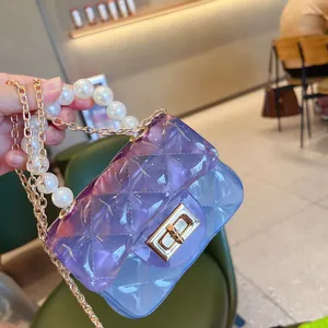 Primo piano di una mini borsa in PVC trasparente con manico di perle e catena d'oro.