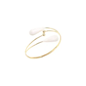 Vue macro détaillée d'un bracelet de bras croisé doré avec des gouttes d'eau blanches
