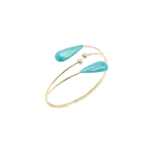 Détail d'un bracelet de bras croisé doré multicouche avec des accents de gouttes bleues