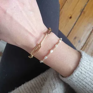Détail de bracelets superposés en chaîne trombone dorée et perles d'eau douce fines
