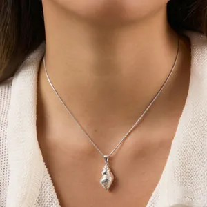 Macro detail shot of a silver-toned conch shell pendant necklace worn by a female model