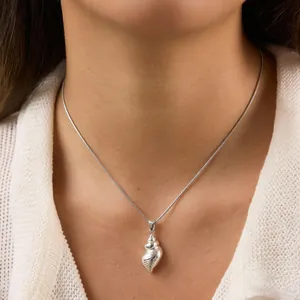Close-up view of a silver conch seashell pendant necklace worn on a female neck.