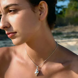 Detailed view of a silver stainless steel seashell pendant necklace on a model's neck.