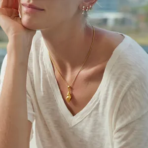 Golden stainless steel shell necklace worn by model showing elegant jewelry details