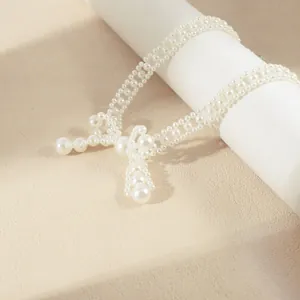 Detailed macro view of woven white pearl choker necklace with cross pendant design