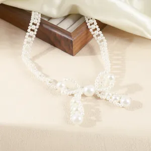 Detail view of an elegant white pearl bowknot choker necklace on silk background