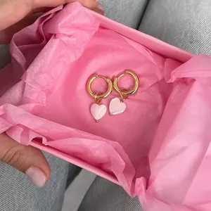Detailed view of elegant gold heart hoop earrings with pink shell charms in a gift box