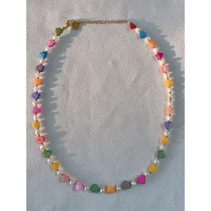 Detail shot of a handmade necklace featuring colorful shell heart beads and pearls