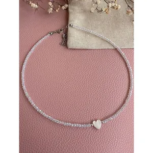 Close-up of handmade beaded necklace with shell heart pendant and clear faceted beads