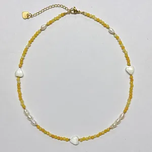 Detailed macro view of handmade yellow beaded necklace with white shell heart charms