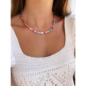 Close-up detail of a colorful handmade shell heart beaded necklace on a model neck
