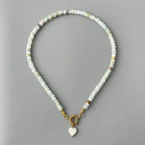 Detailed view of handmade beaded necklace with a white shell heart pendant and gold clasp