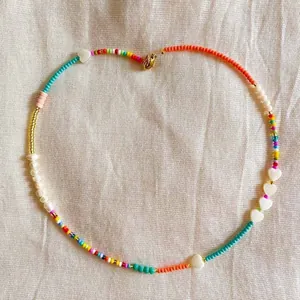 Detailed view of handmade colorful beaded necklace with shell heart and pearl accents.