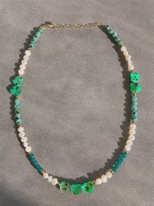 Detail view of handmade beaded necklace with green shell heart pendants and pearls.