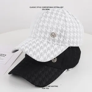 Close-up van zwart-witte kanten baseballcaps voorzien van een glanzend M-logo