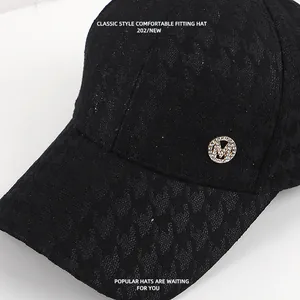 Detailopname van een zwarte kanten honkbalpet met een glanzend strass-steentjes M-logo