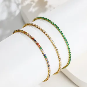 Detailopname van drie fijne vergulde tennisarmbanden met gekleurde zirkonia-stenen.