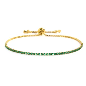 Detail van een delicate goudkleurige kettingarmband met kleine groene ronde kristallen