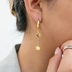 Close-up view of elegant golden star-shaped stainless steel earrings with zircon inlay
