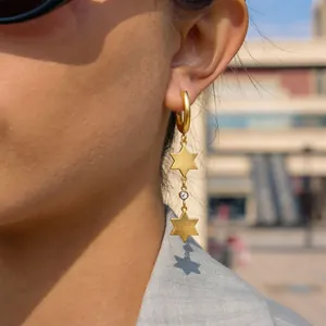 Close-up of elegant gold stainless steel star drop earrings with a sparkling crystal detail