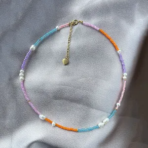 Close-up of colorful beaded necklace with natural pearls and a gold heart charm