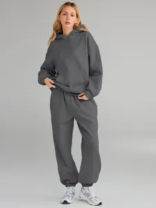 Full body view of a woman wearing a grey two-piece hoodie and sweatpants tracksuit set