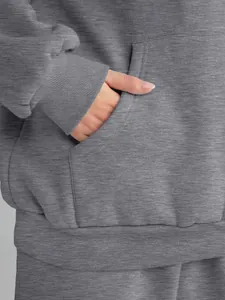 Close-up detail of the grey hoodie pocket and ribbed cuff on a women's casual tracksuit