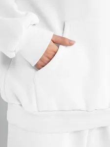 Detail shot of a white women's oversized hoodie featuring a kangaroo pocket and ribbed cuffs.