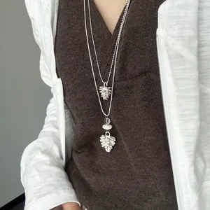 Primer plano de un collar de capas minimalista con colgantes de piña en tonos blanco y plateado
