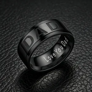 Detail view of 8mm black stainless steel ring with Dad engraving on leather background