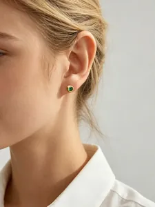 Gros plan d'une boucle d'oreille en argent s925 avec un zircon vert sur l'oreille