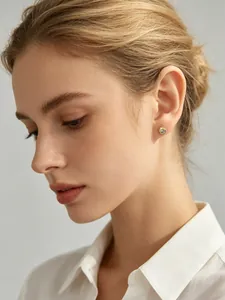Gros plan d'une élégante boucle d'oreille en argent s925 plaqué or avec zircon sur l'oreille