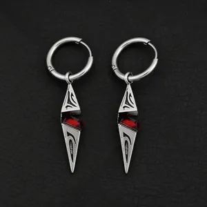 Macro detail of silver hoop earrings featuring red zircon geometric pointed pendants.